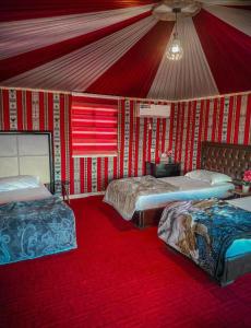 a room with two beds in a room with red walls at Night Magic Camp in Wadi Rum