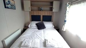 a small bedroom with a bed with a black pillow at Suki - up to 6 berth cabin, new. in Tain