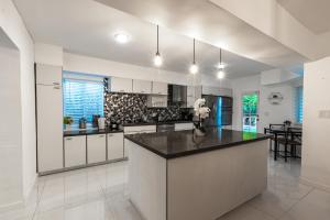 a kitchen with white cabinets and a black counter top at Luxe Villa MiniGolf Pool FirePit in Aventura