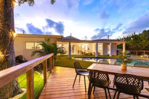 a wooden deck with chairs and a table in front of a house at Luxe Villa MiniGolf Pool FirePit in Aventura