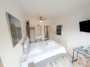 a white bedroom with a bed and a tv at Hotes'Octon in Octon