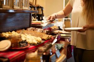 a woman holding a plate of food on a buffet at Almacruz Hotel y Centro de Convenciones (Ex Galerías) in Santiago +49 photos