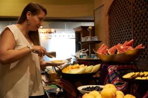 a woman standing in a kitchen preparing food at Almacruz Hotel y Centro de Convenciones (Ex Galerías) in Santiago