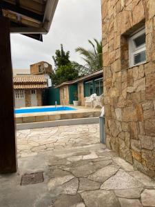 a stone building with a swimming pool in a yard at Pousada Riviera in Caraguatatuba