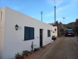 a white building with a black window and a car at Casa Jardim in Ponta do Pargo