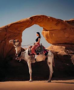 a woman riding on a camel in the desert at Night Magic Camp in Wadi Rum