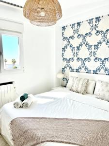 ein Schlafzimmer mit einem weißen Bett mit einer blau-weißen Wand in der Unterkunft Huelin Park Apartment in Málaga