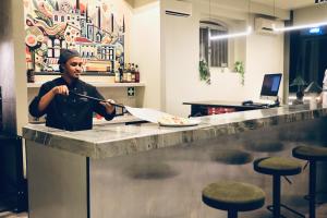 a man standing at a counter holding a knife at Gspot Hostels & Love Triangles Pizzeria in Lisbon
