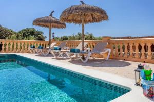 a swimming pool with chairs and umbrellas next to a swimming pool at Sa Madoneta in Santanyi