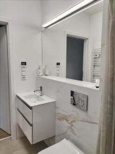 Baño blanco con lavabo y espejo en Piaskowa 13 - Apartamenty dla Podróżujących bez Dzieci en Nickelswalde