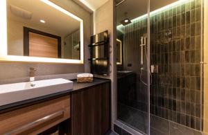 a bathroom with a sink and a shower with a mirror at Woodside Apartment in Kopaonik