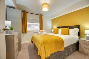 a bedroom with a large bed with yellow walls at Charltons Bonds Apartments 14 by Week2Week in Newcastle upon Tyne