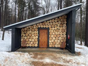 Cabaña de madera con puerta y 2 sillas en Trekker, Treehouses cabins and lodge rooms, en Lake George