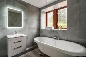 uma casa de banho com uma banheira branca e um lavatório. em Long Ashes - Netherside Barn em Tattenhall
