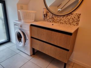 W łazience znajduje się pralka i lustro. w obiekcie Gîte Chez Marie T 6 personnes w mieście La Boussac
