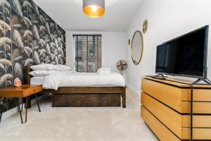 a bedroom with a bed and a tv and a dresser at Chic Urban Apartment In Shoreditch 2 bed 2 bath in London