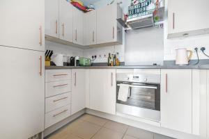 cocina blanca con armarios blancos y horno en Chic Urban Apartment In Shoreditch 2 bed 2 bath, en Londres