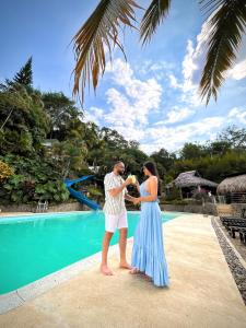 Ein Mann und eine Frau stehen vor einem Pool in der Unterkunft Jungla EcoLuxury Resort in Villeta