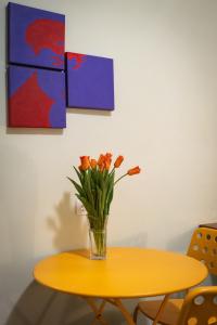un vase de fleurs orange assis sur une table jaune dans l'établissement Casetta Ponte Milvio, à Rome