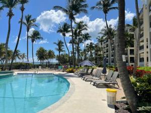 a pool at the resort with chairs and palm trees at Beachfront Luxury 2 Bedroom at Wyndham Rio Mar, PR in Luquillo