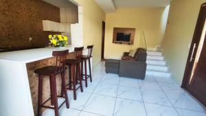 eine Küche mit einer Bar mit Stühlen und einem Sofa in der Unterkunft casa pra muito gente in Tibau do Sul