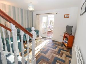 a living room with a staircase and a tv at Hillside Hideaway in Wigton