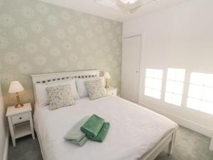 a bedroom with a white bed with two towels on it at Hillside Hideaway in Wigton