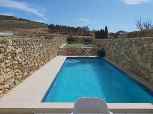 a swimming pool next to a stone wall at Azure in Għarb