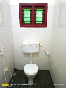 a bathroom with a toilet and a window at NNP Home Stay Rameswaram in Rāmeswaram