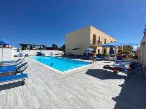 a swimming pool with chairs and umbrellas next to a building at Appartamento Valentina in San Vito lo Capo
