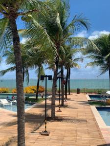 una fila de palmeras junto a una piscina en Cobertura Resort In Mare Bali -Muriú 434 Praia de Cotovelo, en Parnamirim