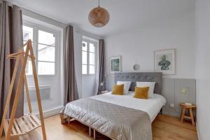 a bedroom with a large white bed with yellow pillows at Louvre Montorgueuil Historical center 3BR II in Paris