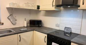 a small kitchen with a stove and a microwave at Spacious Modern Apartment in St. Andrews