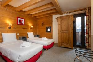 2 letti in una camera con pareti in legno di Le Saint Antoine a Les Houches