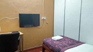 Zimmer mit einem Bett und einem TV an der Wand in der Unterkunft Musafir Transit Hotel in Nilai