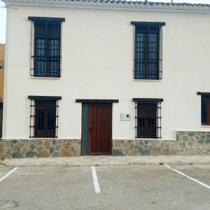 un edificio blanco con una puerta y ventanas marrones en Casa rural El Molino 2 en Alatoz