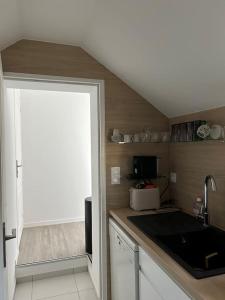 a kitchen with a counter with a sink and a door at appartement 50 mètres de la mer in Jullouville-les-Pins