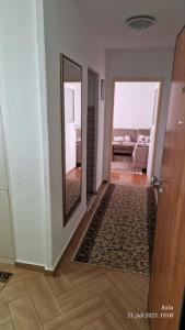 a hallway with a door and a mirror and a living room at Apartman Cowabunga in Sarajevo