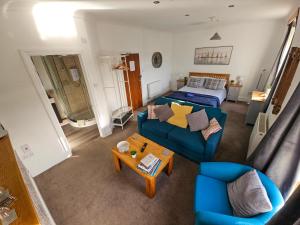 a living room with a blue couch and a bed at Beachcomber B&B in Tenby