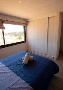 a bed in a small room with a towel on it at Kinesurf cabaña con vista al mar in Pichilemu