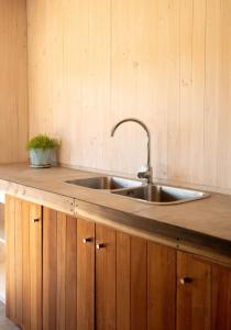 a kitchen with a stainless steel sink and wooden cabinets at Kinesurf cabaña con vista al mar in Pichilemu