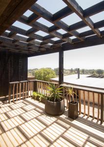 a deck with potted plants and a wooden roof at Kinesurf cabaña con vista al mar in Pichilemu