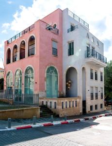 um edifício rosa e branco com uma escada em frente em Jaffa Port TLV Hotel Apartments יפו תל אביב em Tel Aviv