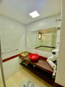 La salle de bains est pourvue d'un lavabo rouge et d'un miroir. dans l'établissement Solar pipa duplex lua cheia, à Pipa