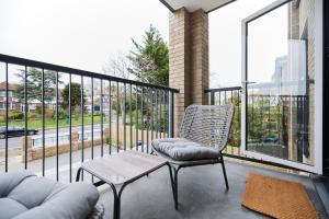 uma varanda com uma cadeira, uma mesa e uma janela em The Wembley Park Gem - Lovely 2BDR Flat with Balcony em Londres