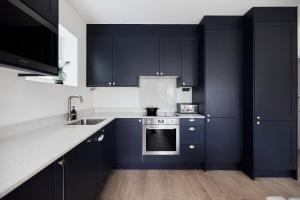 a kitchen with navy blue cabinets and white counter tops at The Wembley Park Gem - Lovely 2BDR Flat with Balcony in London