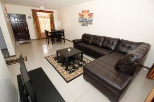 uma sala de estar com um sofá de couro e uma mesa em Lux Suites Milimani Executive Apartments Nakuru em Nakuru