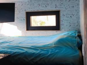 a bedroom with a blue bed with a window at Tiny House Montenegro in Petrovac na Moru