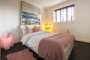 a bedroom with a large bed with pink pillows at 4 Bed Townhouse 2 mins from everything & 1 parking space! in Stratford-upon-Avon
