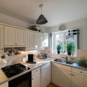 a kitchen with white cabinets and a sink at 4 Bed Townhouse 2 mins from everything & 1 parking space! in Stratford-upon-Avon